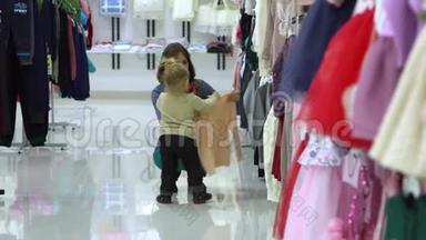一个可爱的小女孩和她的母亲在一家精品店里家精品店。 妈妈和孩子在商店里选择衣服。